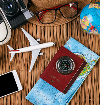 vacation items on table - hat, glasses, globe, passport, mini airplane, map, compass